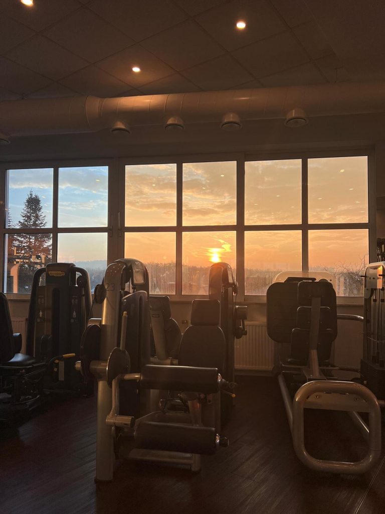 Fitness-Geräte im Fitnessstudio des Sportcentrum Nürnberg vor einer großen Fensterfront, durch die man einen Sonnenuntergang sieht