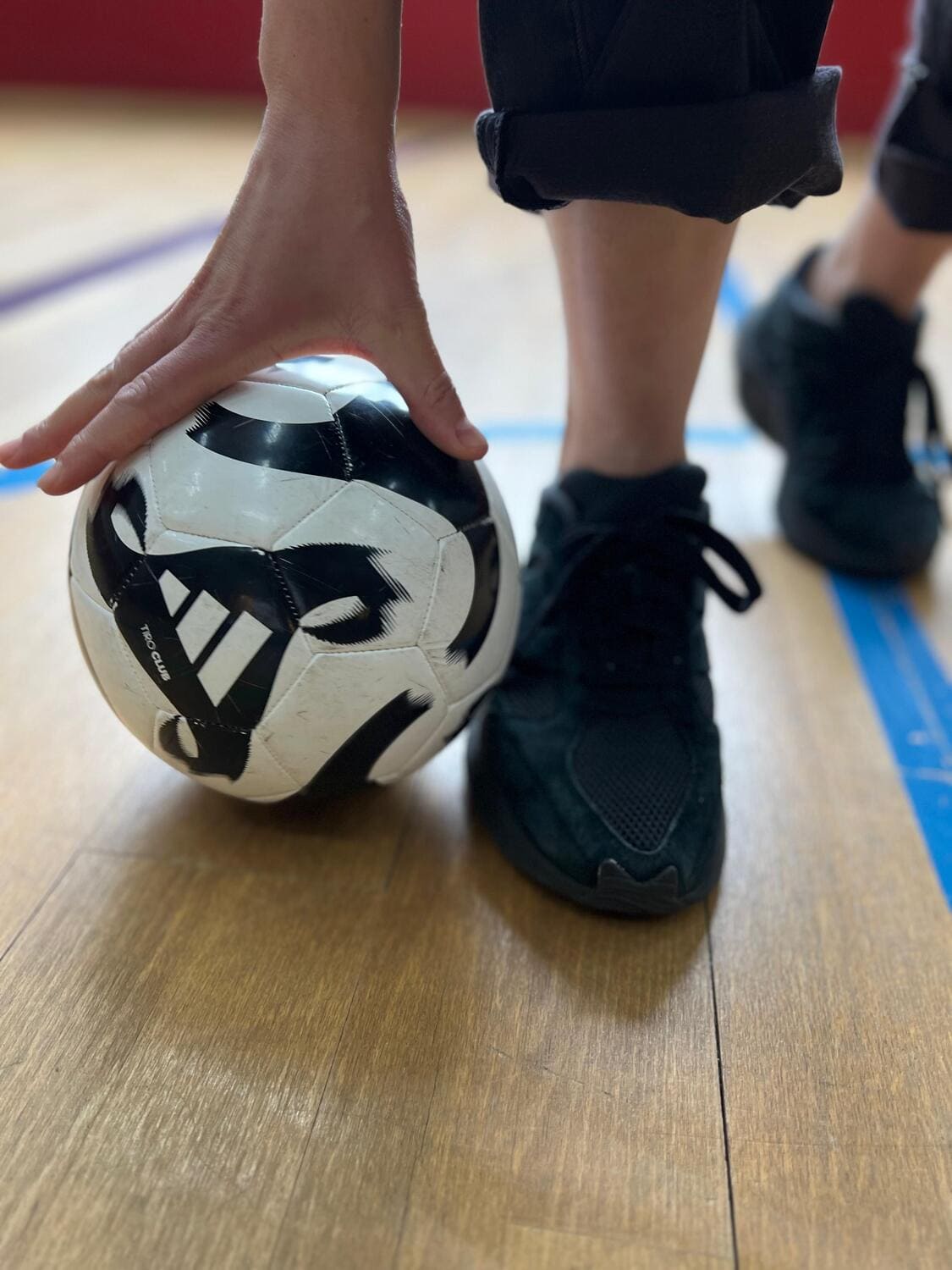 Ein Handball liegt auf dem Boden neben einem Fuß im Sportschuh und eine Hand ruht auf dem Ball im  Sportcentrum Nürnberg