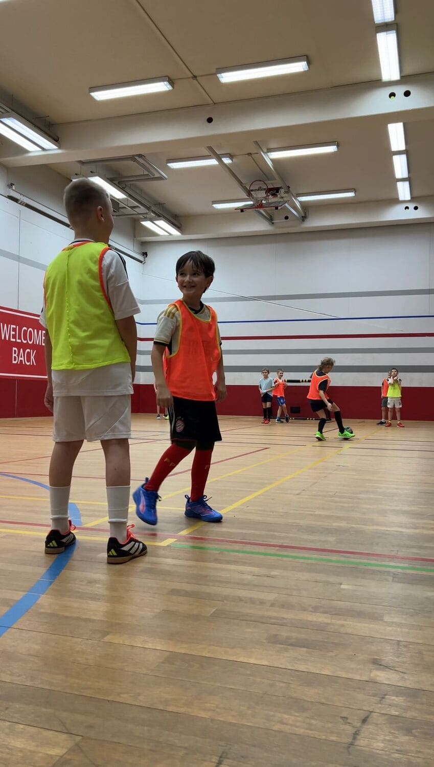Zwei Jungs in unterschiedlichen Leibchen blicken sich an und grinsen beim Multisport Kindersport im Sportcentrum Nürnberg
