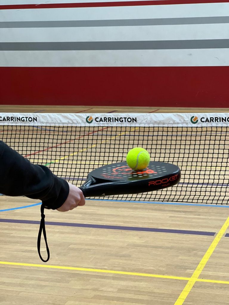 Tennisball liegt auf einem Padel Tennis-Schläger vor dem Tennisnetz im Sportcentrum Nürnberg
