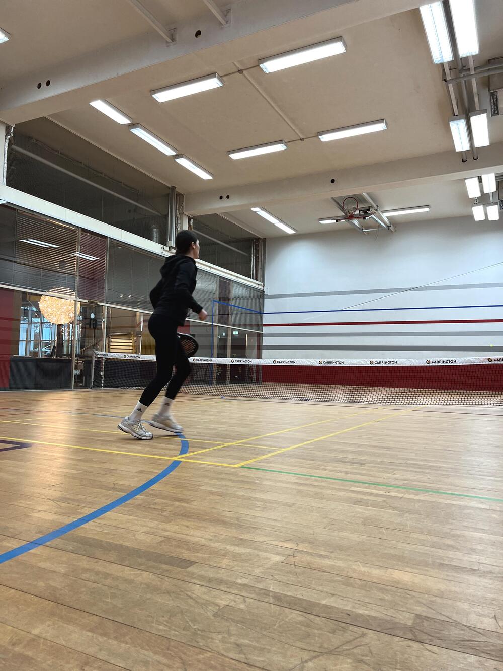 Eine aktive Spielerin steht im Game Court vor dem Netz und wartet auf den Ball