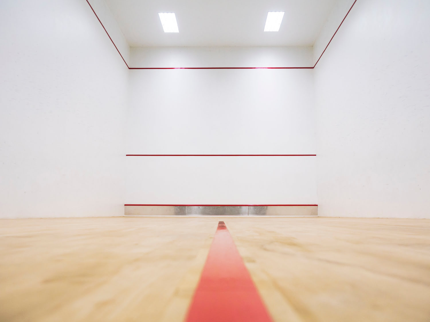 Squash Halle im Sportcentrum Nürnberg mit weißen Wänden und roten Bodenmarkierungen auf Holzbodendielen