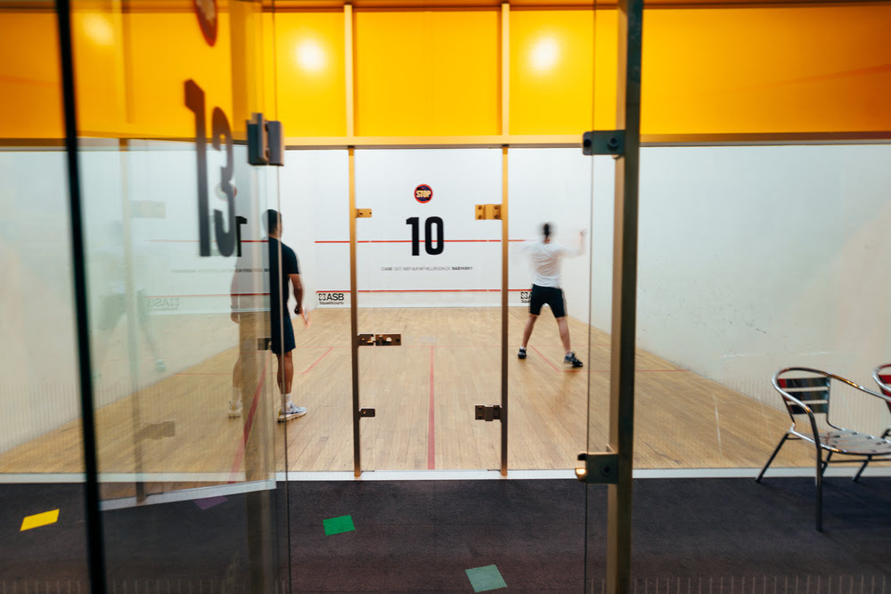 Zwei Männer spielen im Squash Court des Sportcentrums Nürnberg, dessen geschlossene Glastür mit der Nummer 10 versehen ist