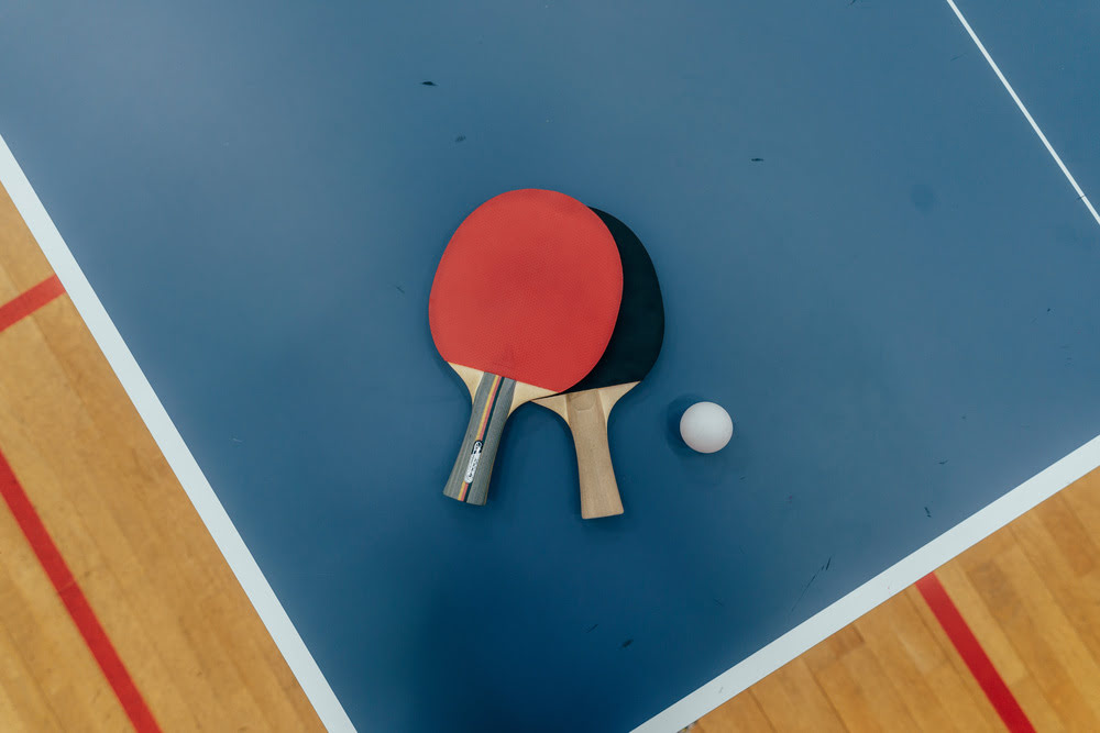 Tischtennis-Platte in blau, auf der zwei Tischtennis-Schläger sowie ein Ball liegen im Tischtennis-Court des Sportcentrum Nürnberg