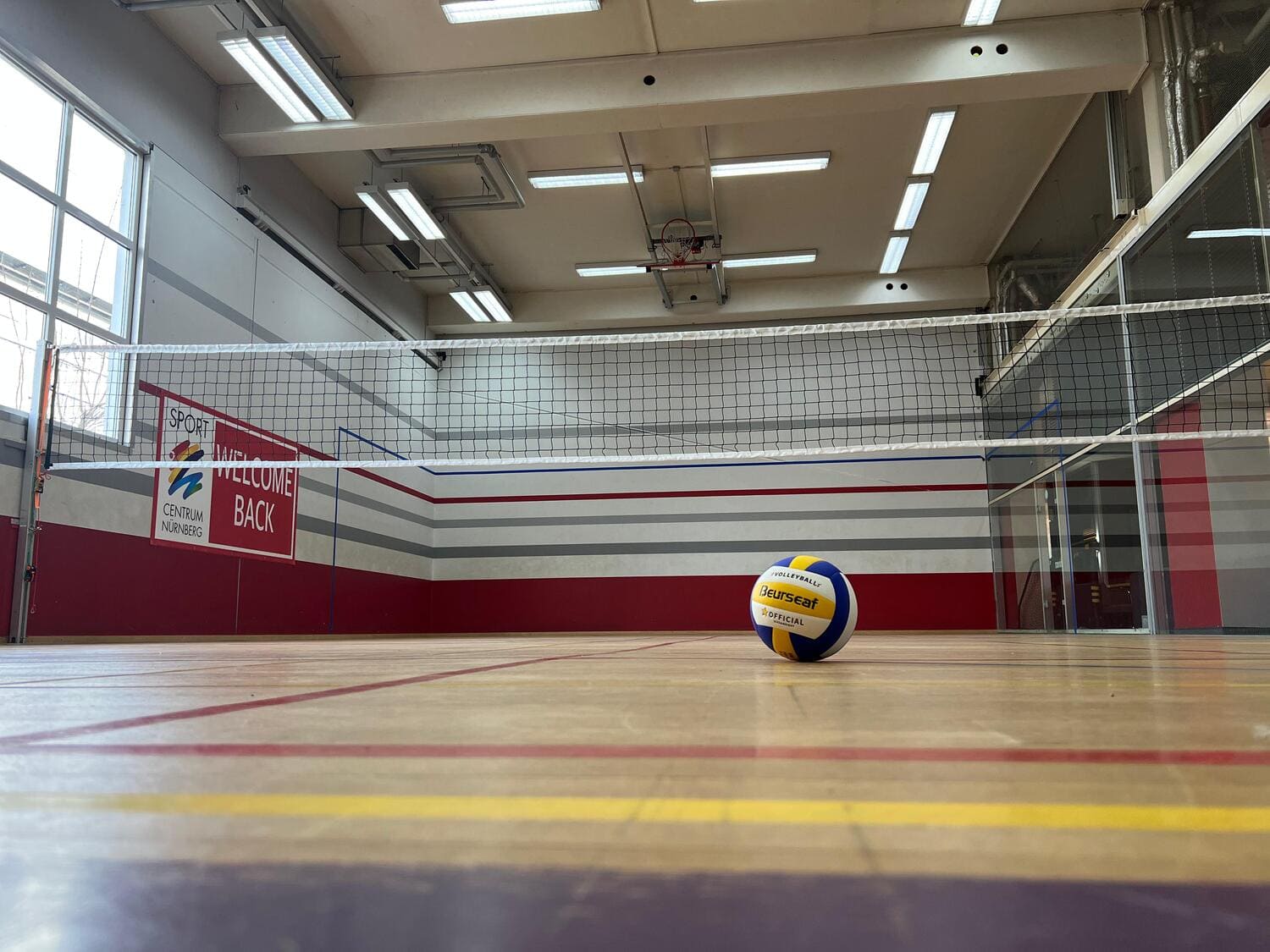 Ein Volleyball liegt auf dem Boden unter dem Volleyball-Netz im Game Court im Sportcentrum Nürnberg 